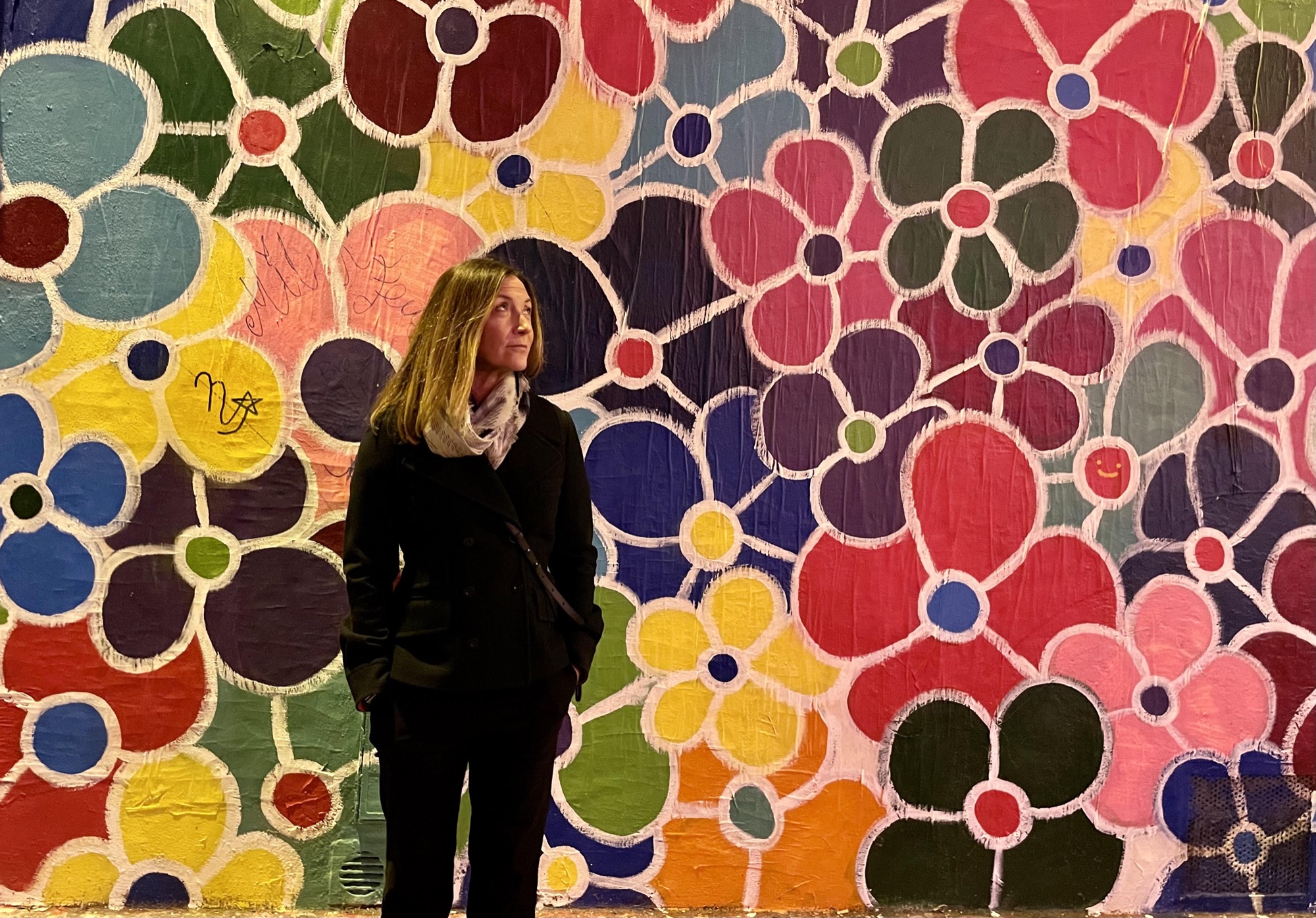 Kris McIntosh standing in front of a painted flower mural